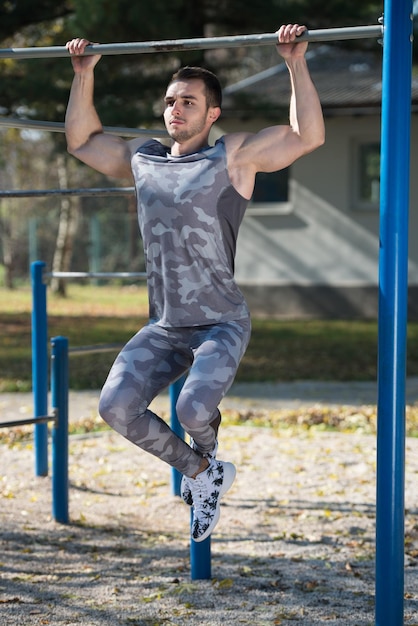 Молодой человек делает кроссфит-упражнения с баром в городском парке, тренируется и тренируется для выносливости Концепция здорового образа жизни на открытом воздухе