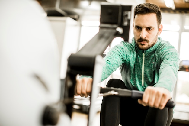 Young man doing exercise for triceps in the gym on mashine