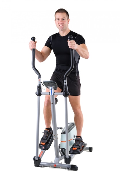 Young man doing exercises on elliptical trainer