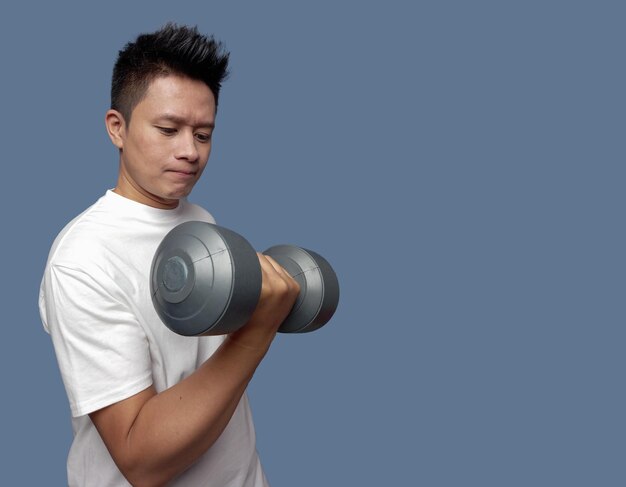 Young man doing exercises using dumbbells isolated on plain background