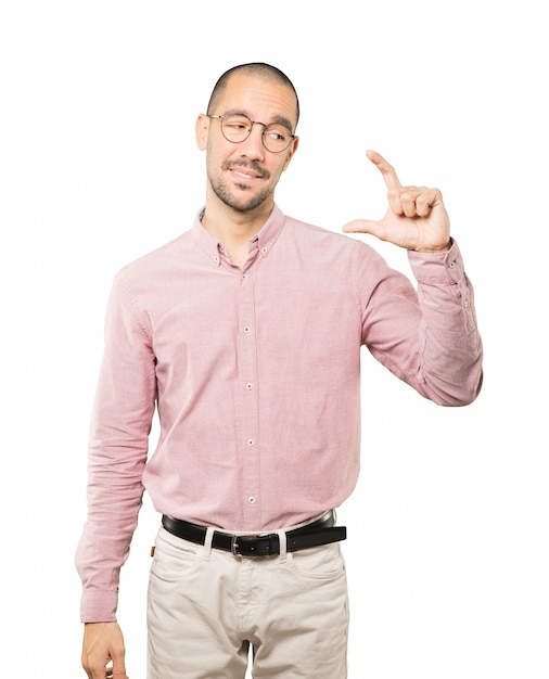 Young man doing a gesture of small size with his hand