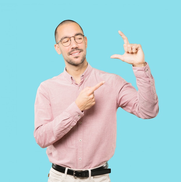 Young man doing a gesture of small size with his hand