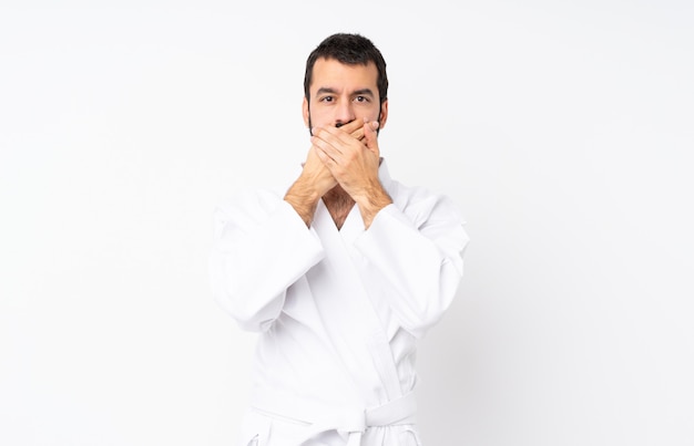 Young man doing karate over isolated white background covering mouth with hands