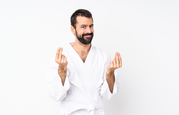 Young man doing karate over isolated white making money gesture