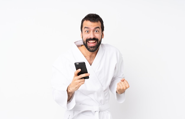 Young man doing karate over isolated white surprised and sending a message