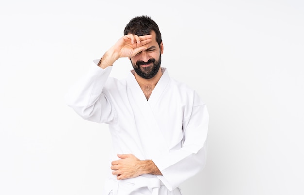 Young man doing karate over isolated white  with tired and sick expression