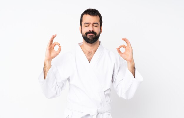 Young man doing karate over isolated  in zen pose