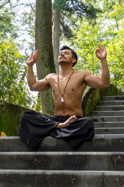 Фото Молодой человек медитирует на лестнице в лесной мексике