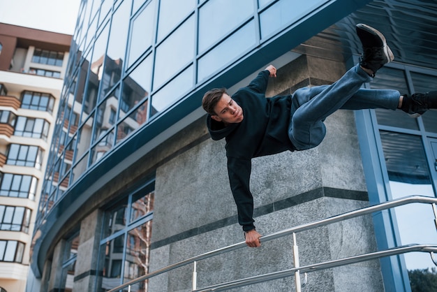 Young man doing parkour in the city at daytime. Conception of extreme sports.