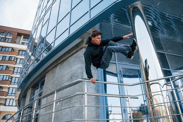 Photo young man doing parkour in the city at daytime. conception of extreme sports.