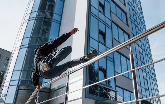 Young man doing parkour in the city at daytime. Conception of extreme sports.