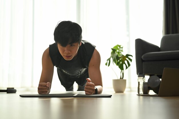 Young man doing plank exercise at home Sport and healthy lifestyle concept