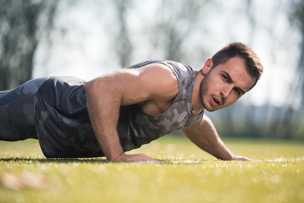 Young Man Doing Pushups in City Park Area  Training and Exercising for Endurance  Fitness Healthy Lifestyle Concept Outdoor