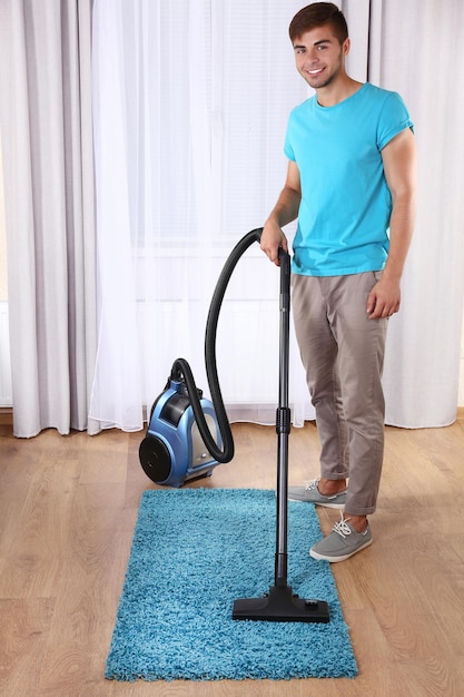 部屋で掃除機をかける若い男