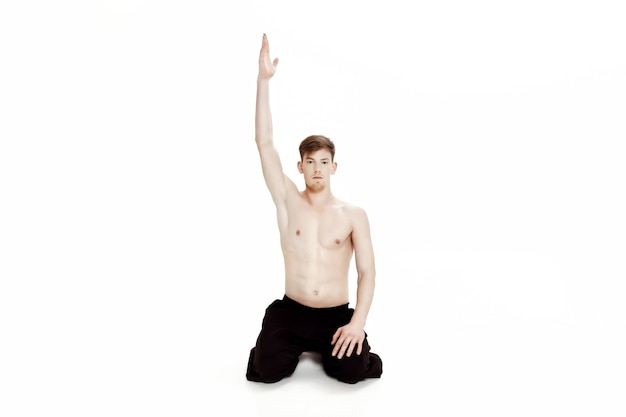 Young man doing yoga exercises studio shot on white background