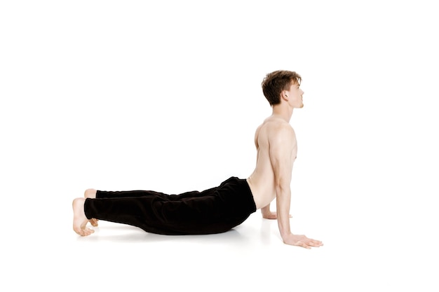 Young man doing yoga exercises studio shot on white background