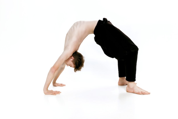 Young man doing yoga exercises studio shot on white background