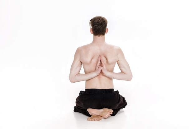 Young man doing yoga exercises studio shot on white background