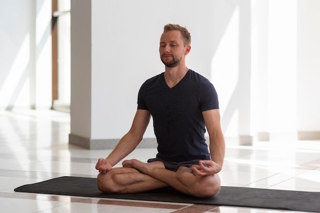 Photo young man doing yoga indoor