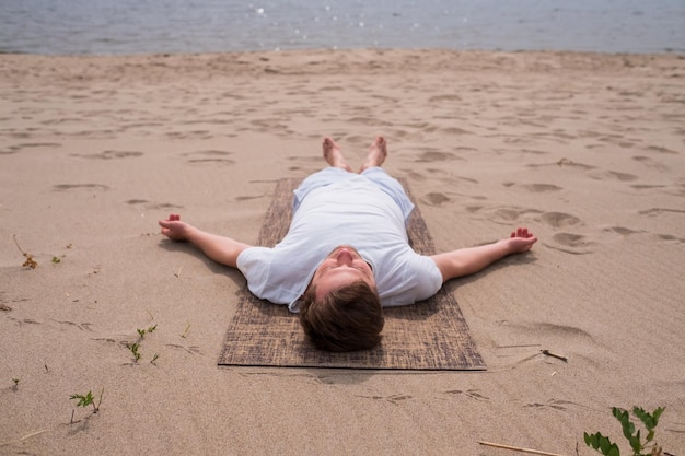 Young man doing yoga on a lake on a summer day meditation relaxation pose