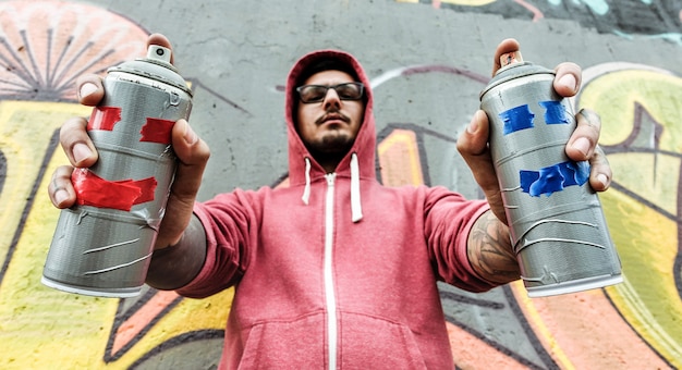写真 若い男がスプレーで描画します。壁にエアロゾル色の缶で絵を描くグラフィティアーティスト