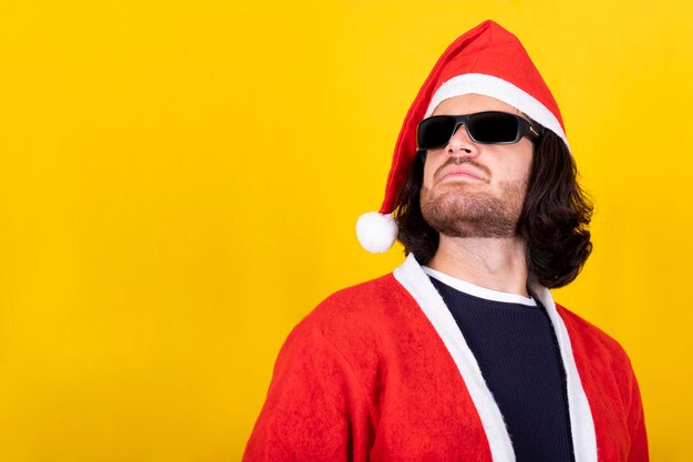 Young man dressed as santa claus has long hair and wears sunglasses