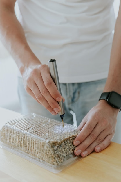 A young man drills a box with a mini drill