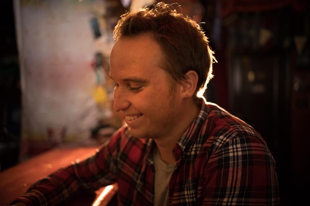 Young man drinking beer at the bar smiling