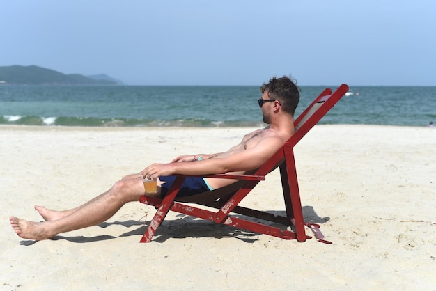 맥주를 마시고 나트랑 해변에서 갑판 의자에 앉아 젊은 남자