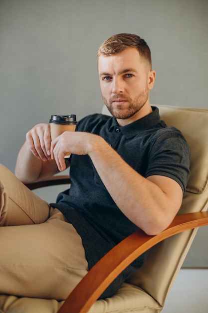 Young man drinking coffee in a comfy chair