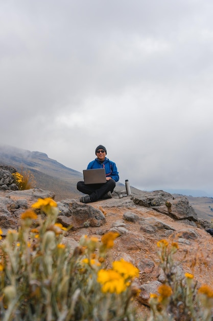 Young man drinking coffee in mountains with laptop. Mountain camping concept.