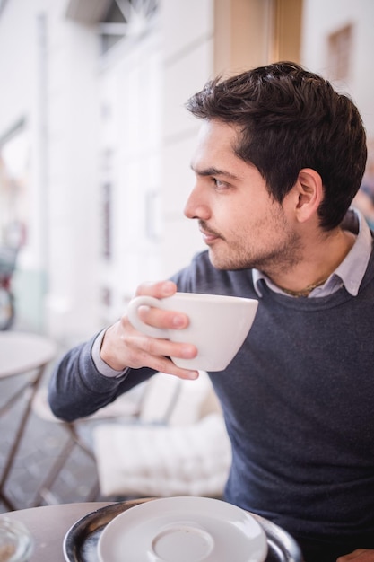 young man drinking coffee at sidewalk cafe