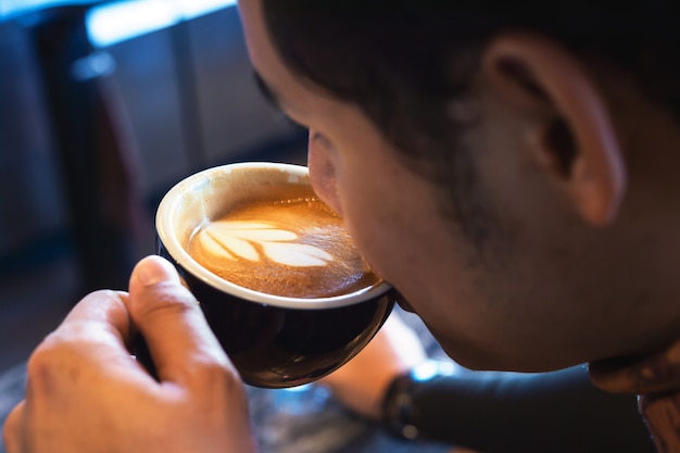 若い男がカフェでホットコーヒーを飲む