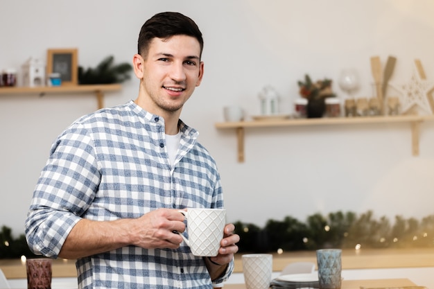 Young man drinking hot drink in kitchen