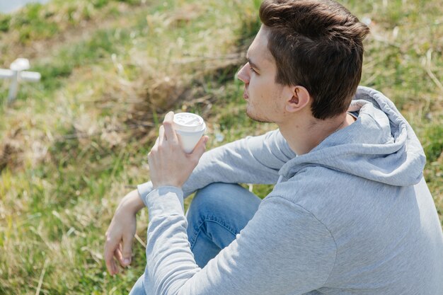 写真 若い男は自然の中でコーヒーを飲む