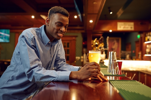 Young man drinks fresh beer at the counter in bar