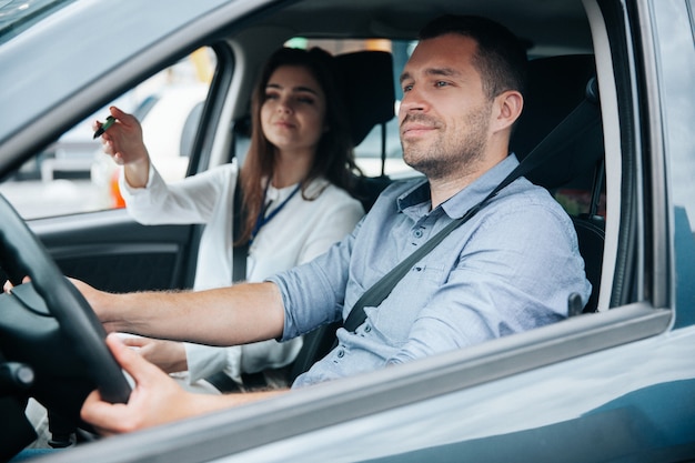 Young man driving a car with his instructor