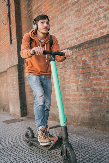 Young man driving electric scooter.