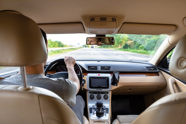 アスファルト道路で現代の車を運転している若い男