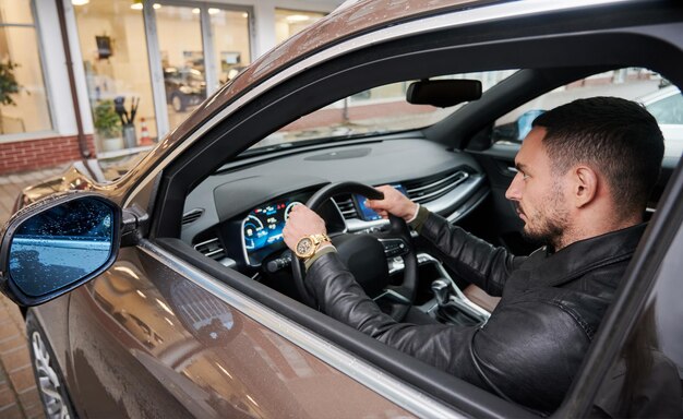 自動車販売店の背景に現代の車を運転する若い男