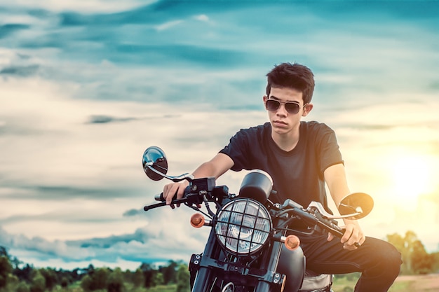 写真 自然の湖のそばでバイクを運転している若い男。