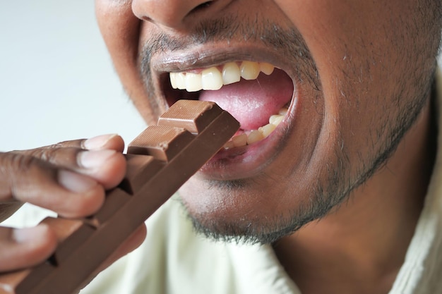 Photo young man eating dark chocolate close up