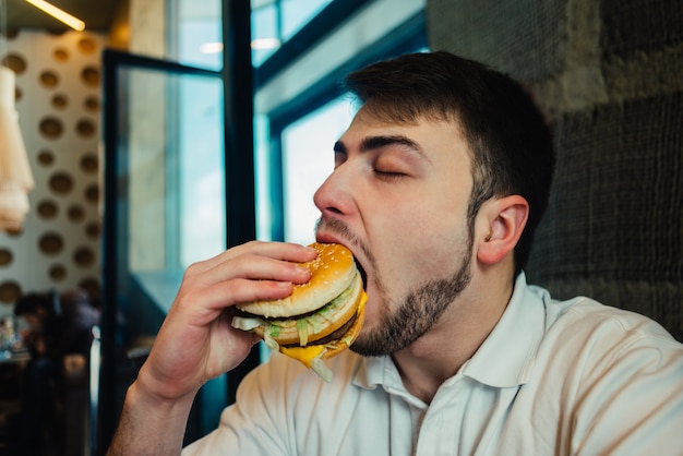 Young man eating a hamburger in a restaurant