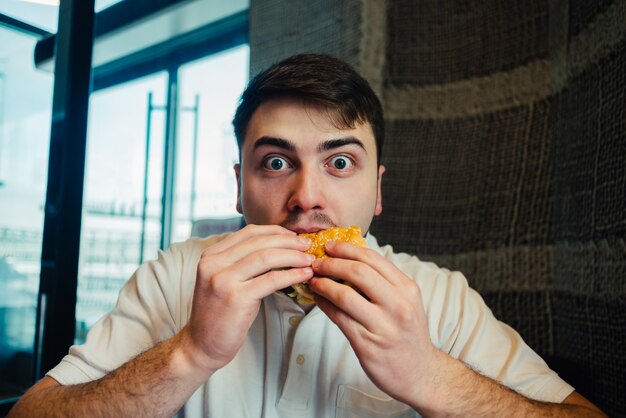 Young man eating a hamburger in a restaurant