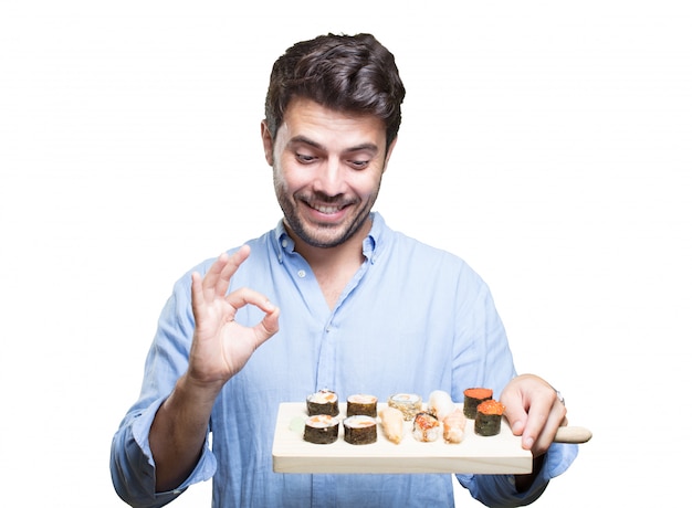 Молодой человек ест суши на белом фоне