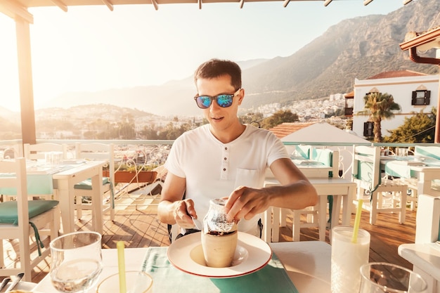 Young man eating Testi kebab in restaurant on a terrace It is an authentic Turkish delicious meat dish baked in a clay pot served after breaking the jug