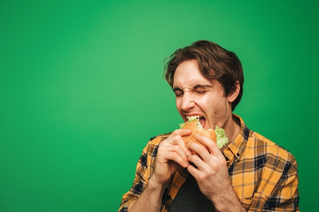 Young man eats burger with pleasure