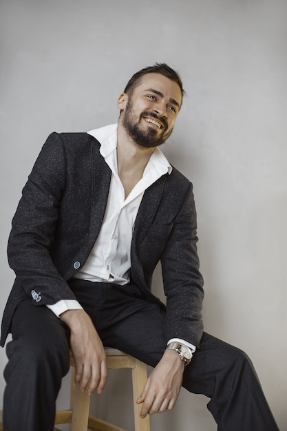 Giovane uomo in un abito elegante in posa in uno studio