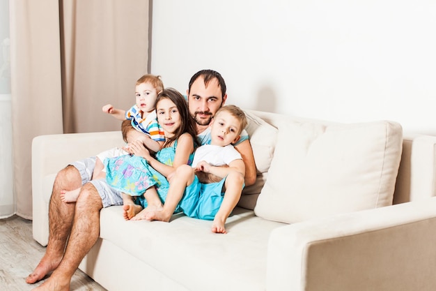 Young man embracing children. Portrait of a caring father with his three kids.