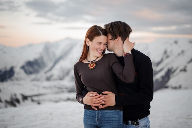 Young man embracing and kissing her girlfriend in mountains